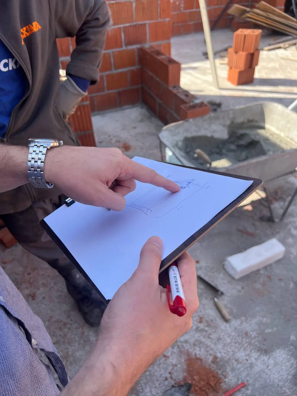Stvarna fotografija: ruke pokazuju detalj skice na gradilištu
